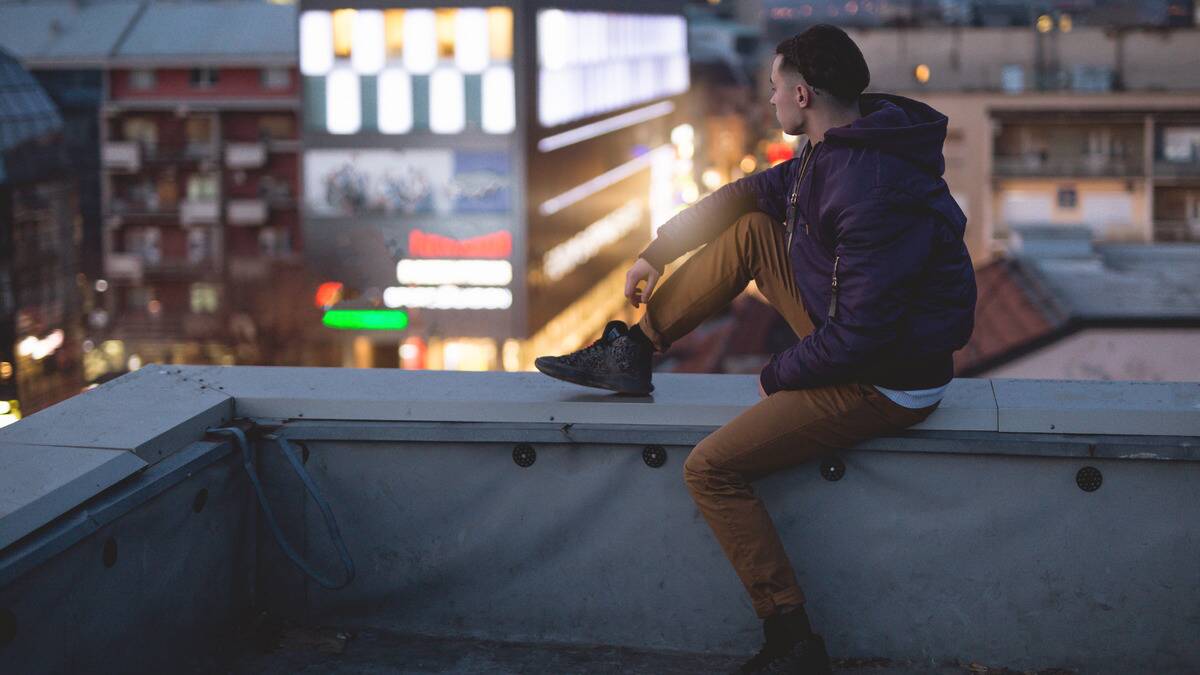 A man sitting on a building's roof, overlooking the city.