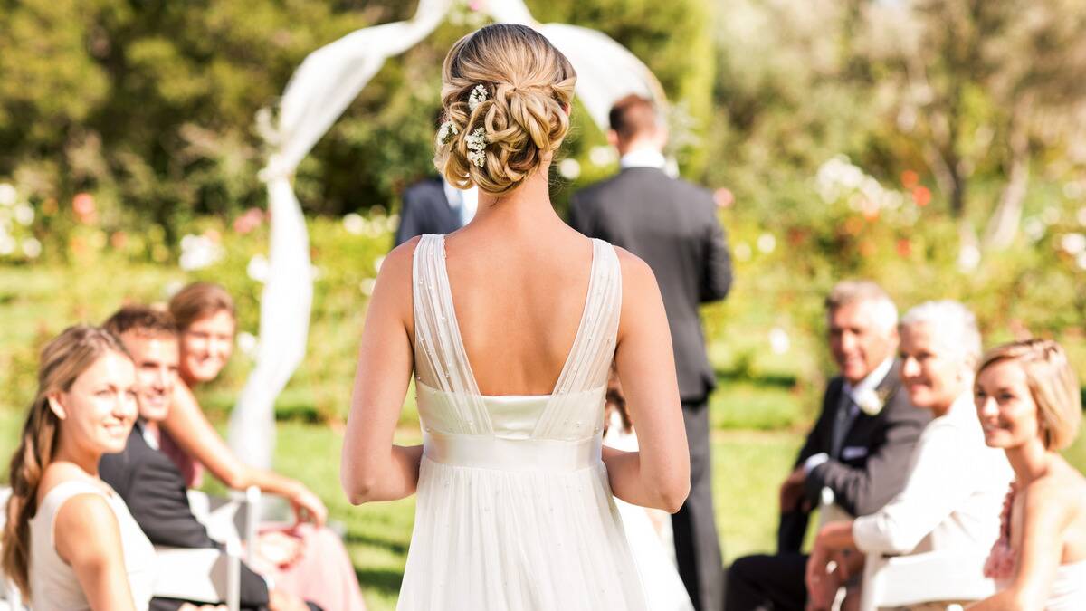 A bride walking down the aidle toward the altar, photographed from behind.