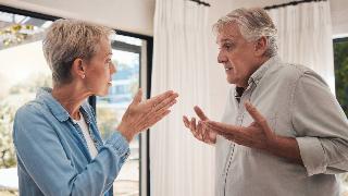 A couple standing close to one another, seemingly having an argument.