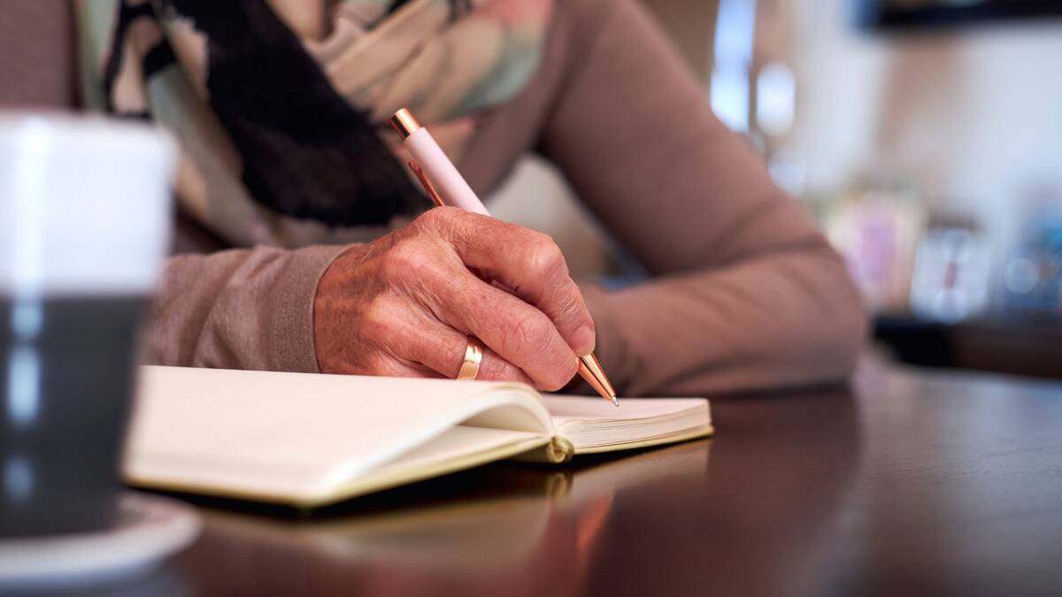 A close shot of a woman writing in a journal.