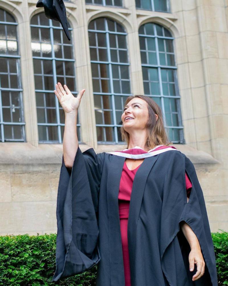 Dr. Bradford tossing her graduation cap in the air for one of her graduation photos.