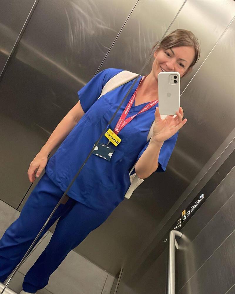 Dr. Bradford taking a selfie in an elevator mirror in her work scrubs.