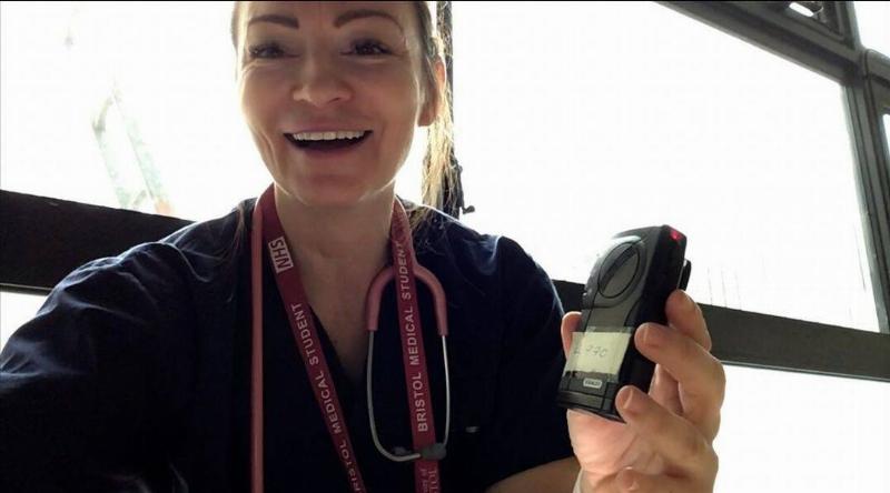 Dr. Bradford smiling and showing off a medical device as she sits in front of a window.