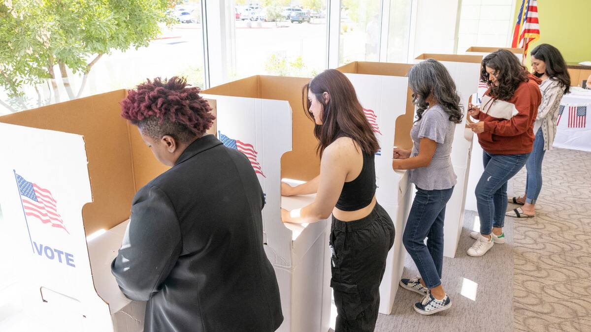 A row of women casting their vote at the polls.