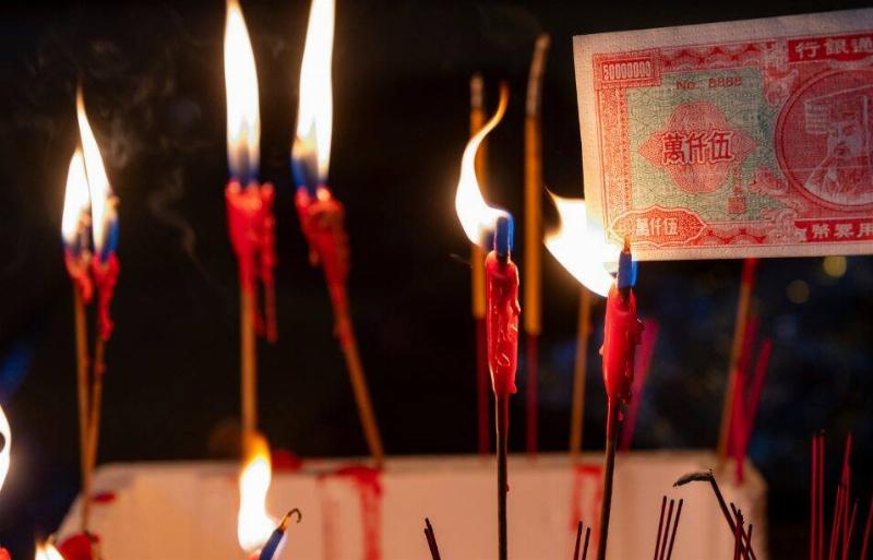 A resident burns paper money during the Hungry Ghost festival.