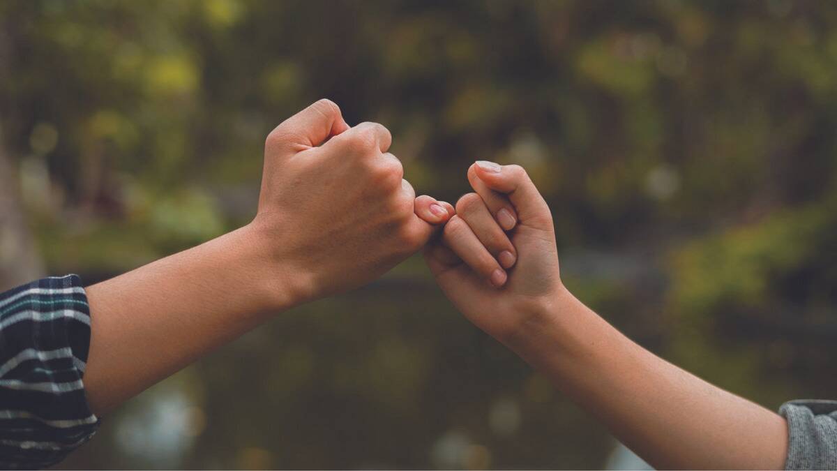 A close shot of a two people making a pinky promise, only their hands being visible.