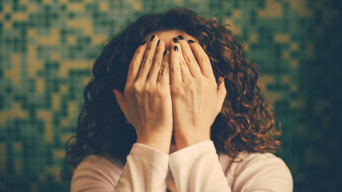 A woman covering her face with both hands.