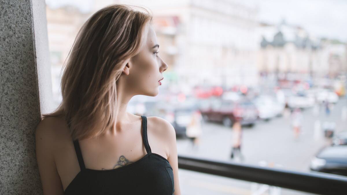 A woman looking over her shoulder out of the window she's sitting next to.