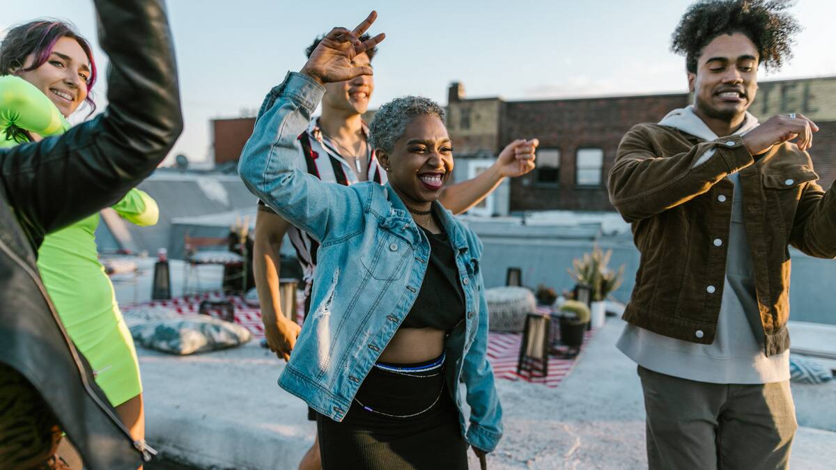 A woman smiling and dancing during a rooftop party.