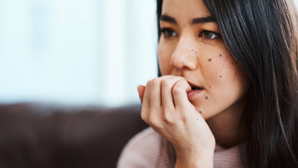 A close shot of a woman biting her nails nervously.