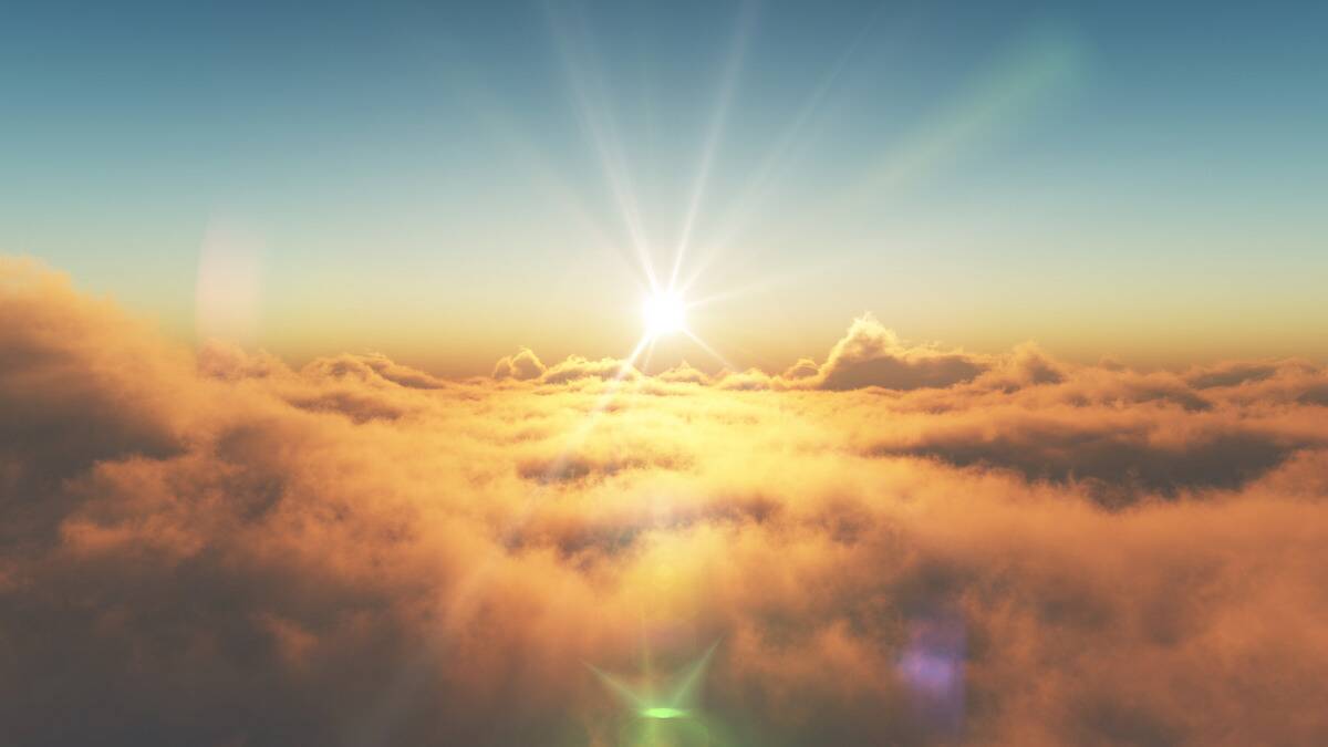 The sun rising over a blanket of clouds, making them appear gold with the sky still blue above them.