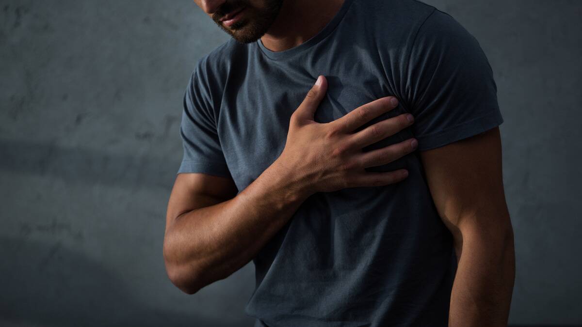 A man slightly bent over with a hand on his chest.