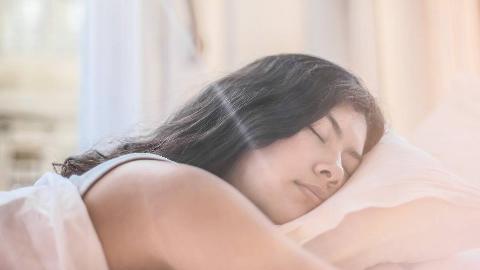 A woman sleeping on her stomach, her head on its side on the pillow.