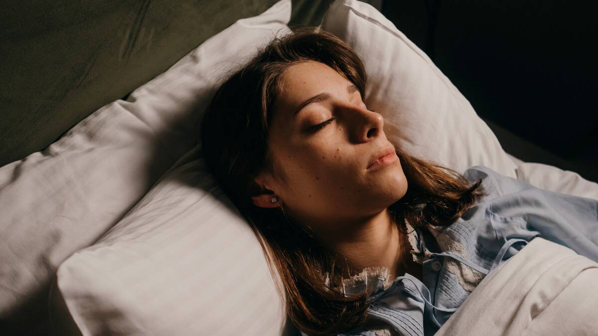 A woman with her head on two pillows, asleep in bed.