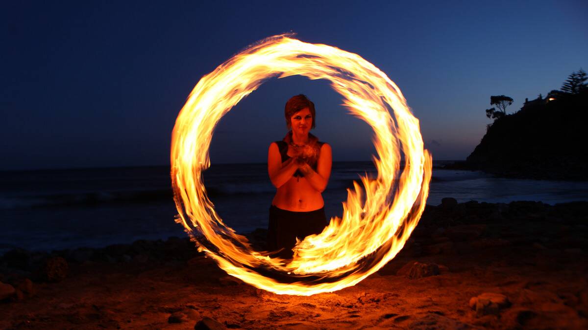 A woman on the beach creating a swirl of fire.