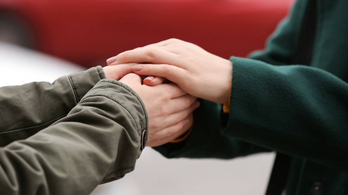 A close shot of two people with their hands together, both seeming to hold onto the other.