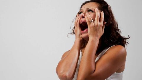 A woman screaming, hands on her face.