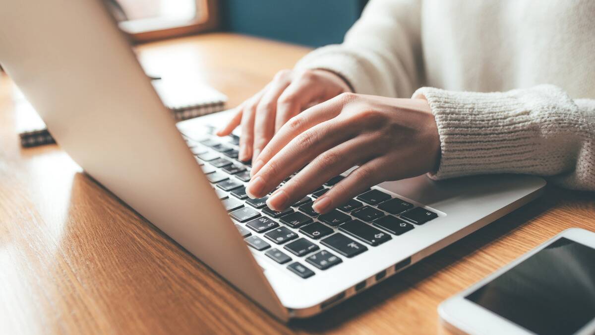 A photo of a pair of hands typing on a laptop.