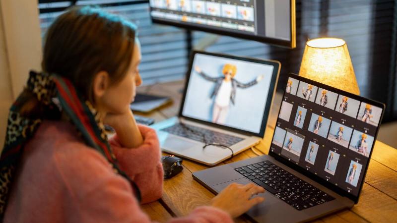 A woman sitting at a laptop doing some photo editing.