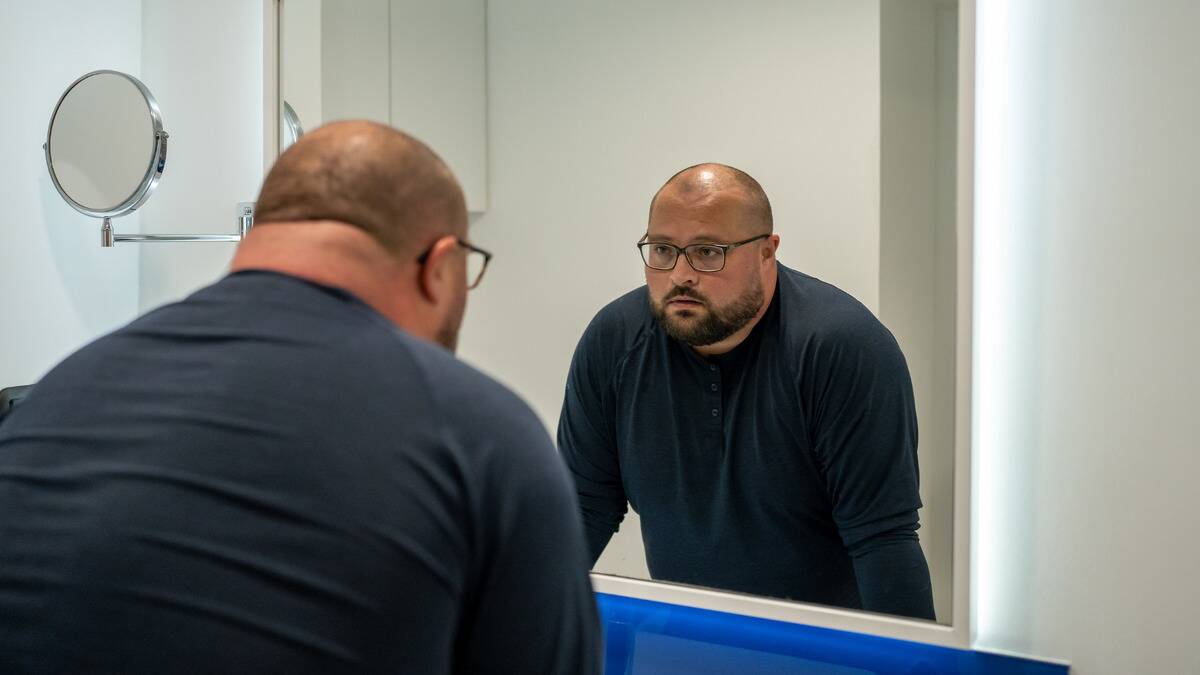 A man looking at himself in the mirror with a concerned expression.