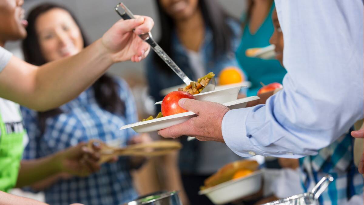 A shot of someone serving a ladle of soup into a bowl that's on a tray of other food.