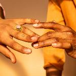 A close shot of two hands touching gingerly in the sun.