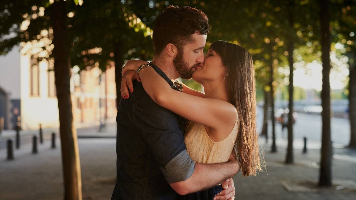 A couple holding each other and kissing in the middle of a street.