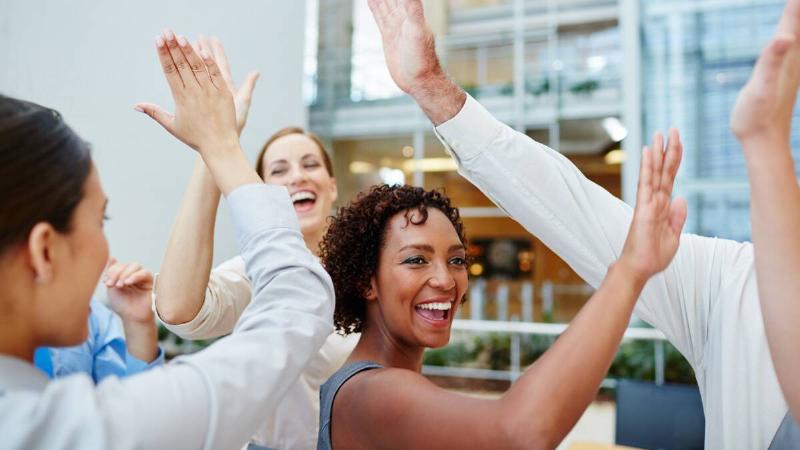 A group of people, likely coworkers, all happily high-fiving.