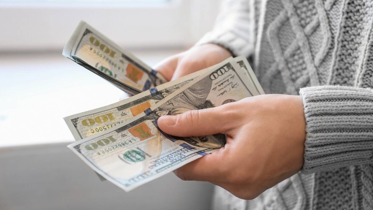 A close shot of a pair of hands counting a stack of $100 bills.