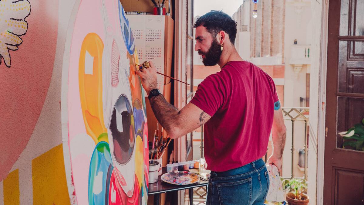 A profile shot of a man painting on a large circular canvas.