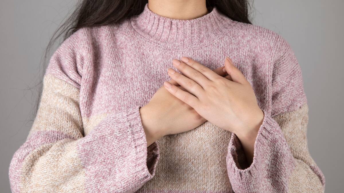 A close shot of a woman playing both her hands over her heart.