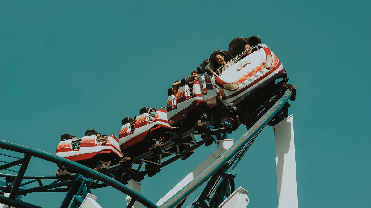 A roller coaster rounding a corner, the people in the seats seen smiling and yelling.