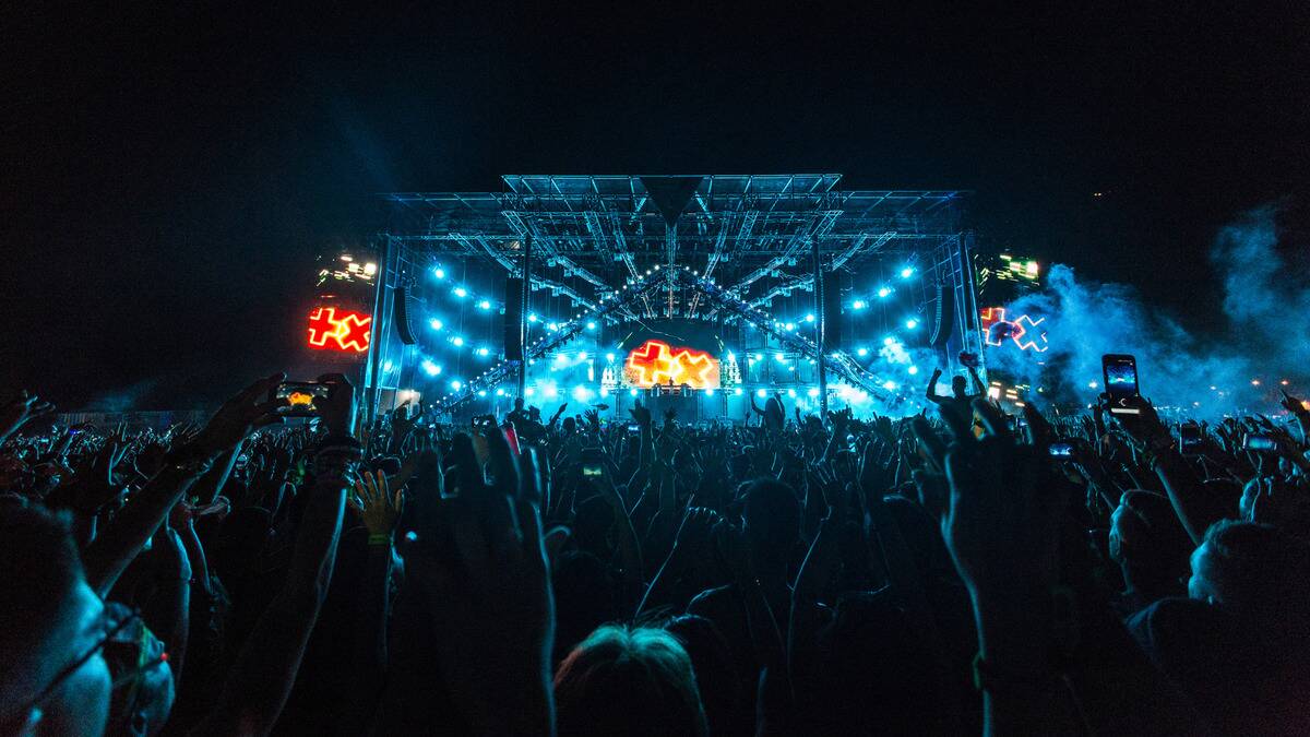 A large concert crowd in front of an also large stage lit up in blue.