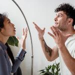 A couple in the midst of arguing, both looking stressed and gesturing dramatically with their hands.