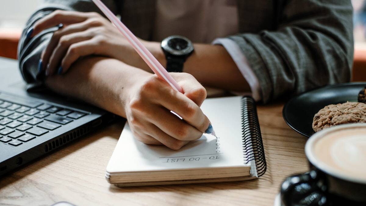 A close shot of someone writing out their to-do list in a notebook.