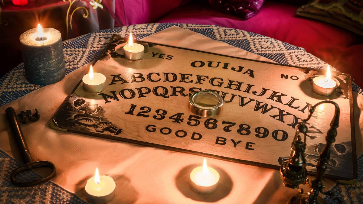 A Ouija board on a table surrounded by candles.