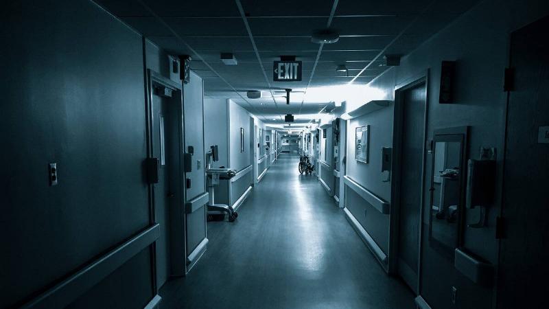 A greyscale shot of a long hospital hallway.