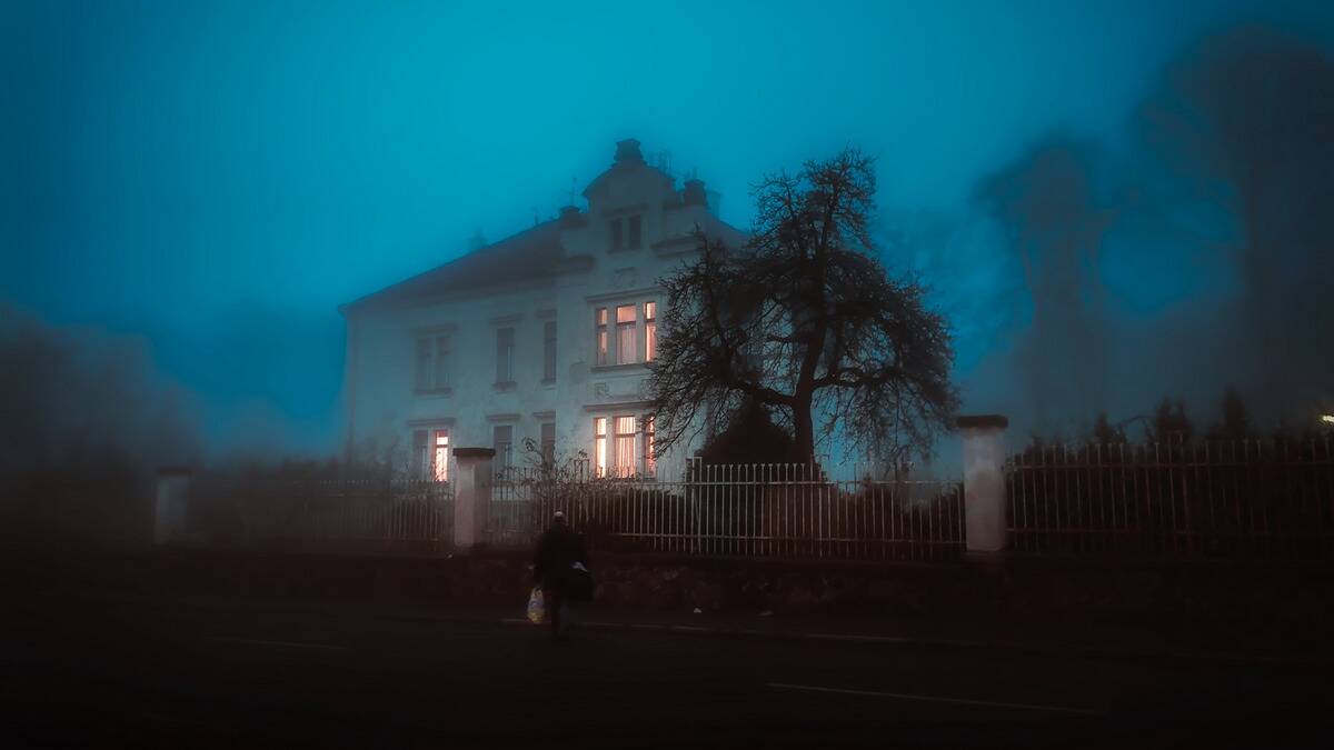 A spooky house in the dark, an eerie fog surrounding it.