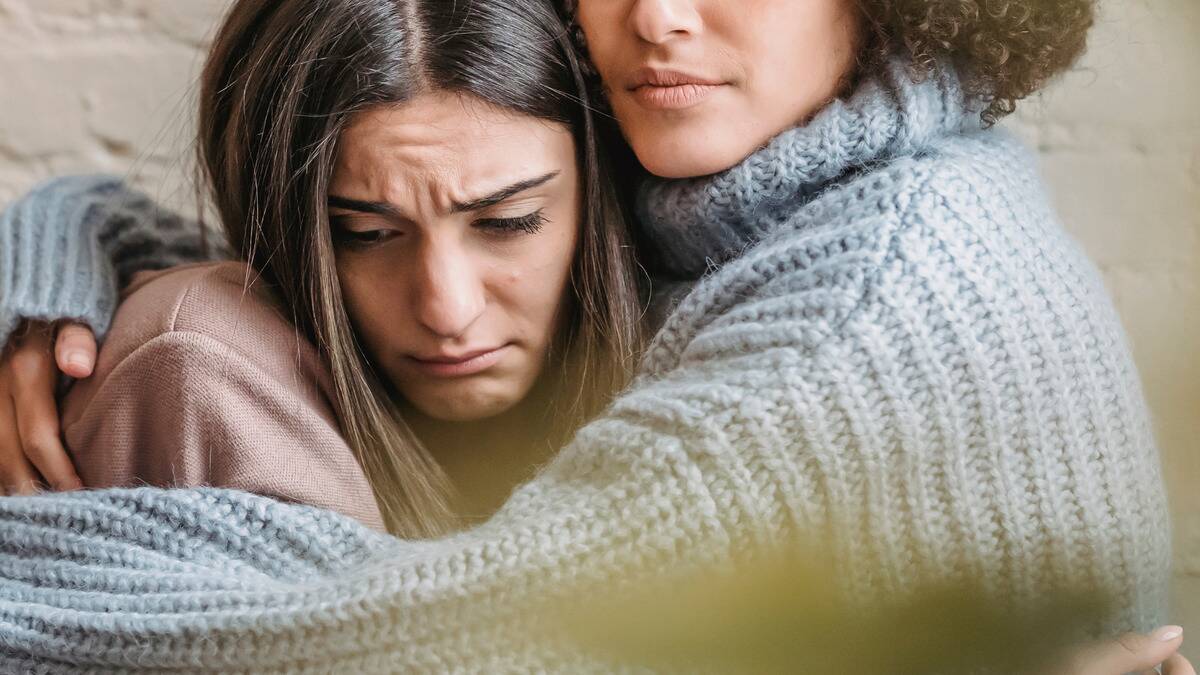 A close shot of a woman hugging her friend who's visibly sad.