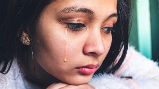 A very close shot of a young girl with a tear running down her cheek.