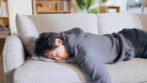 A man sleeping on his stomach on his couch.