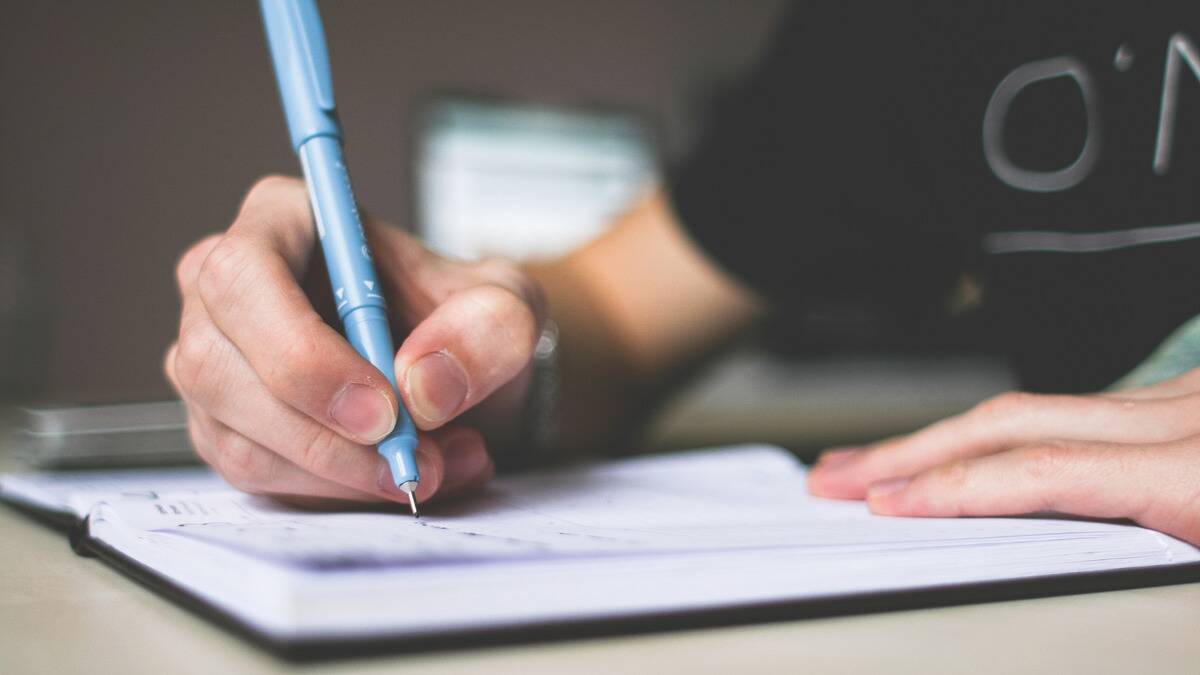 A close shot of someone writing in a notebook with a pen.