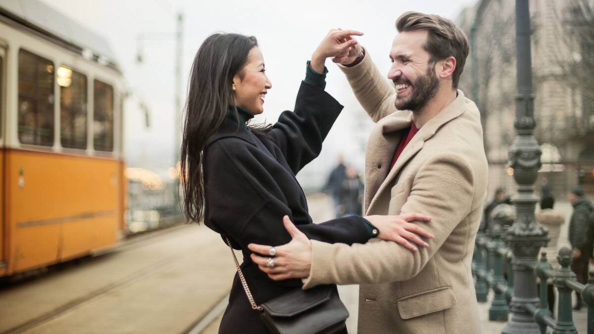 A couple dancing outside, smiling at one another.