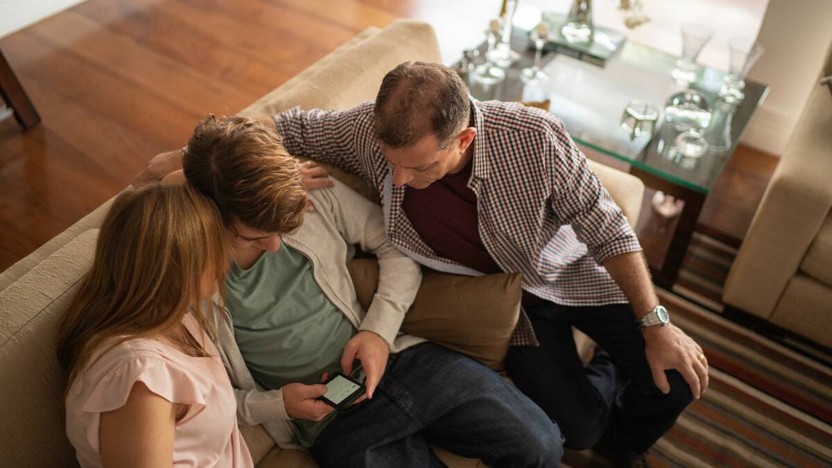 An aerial shot of two parents sitting on either side of their son, leaning in to listen to him speak.