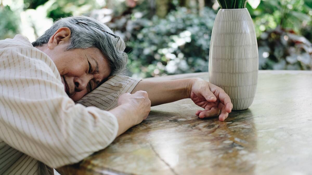 A woman laying against a table, crying with her head resting on her arm.