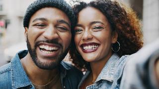 A close photo of a couple standing side by side, temples pressed together, smiling for a selfie.