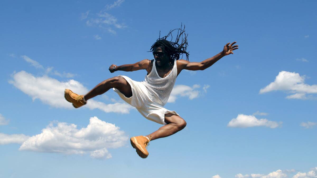 A man jumping high into the air, kicking one of his legs out.