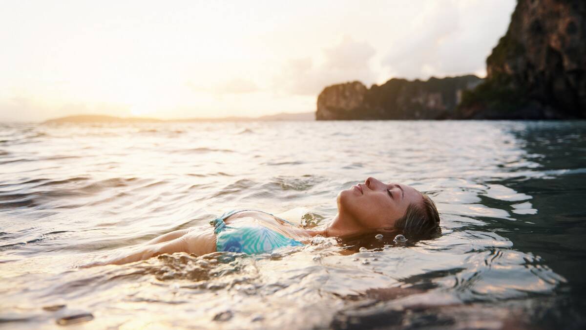 A woman floating serenely in the water, eyes closed.