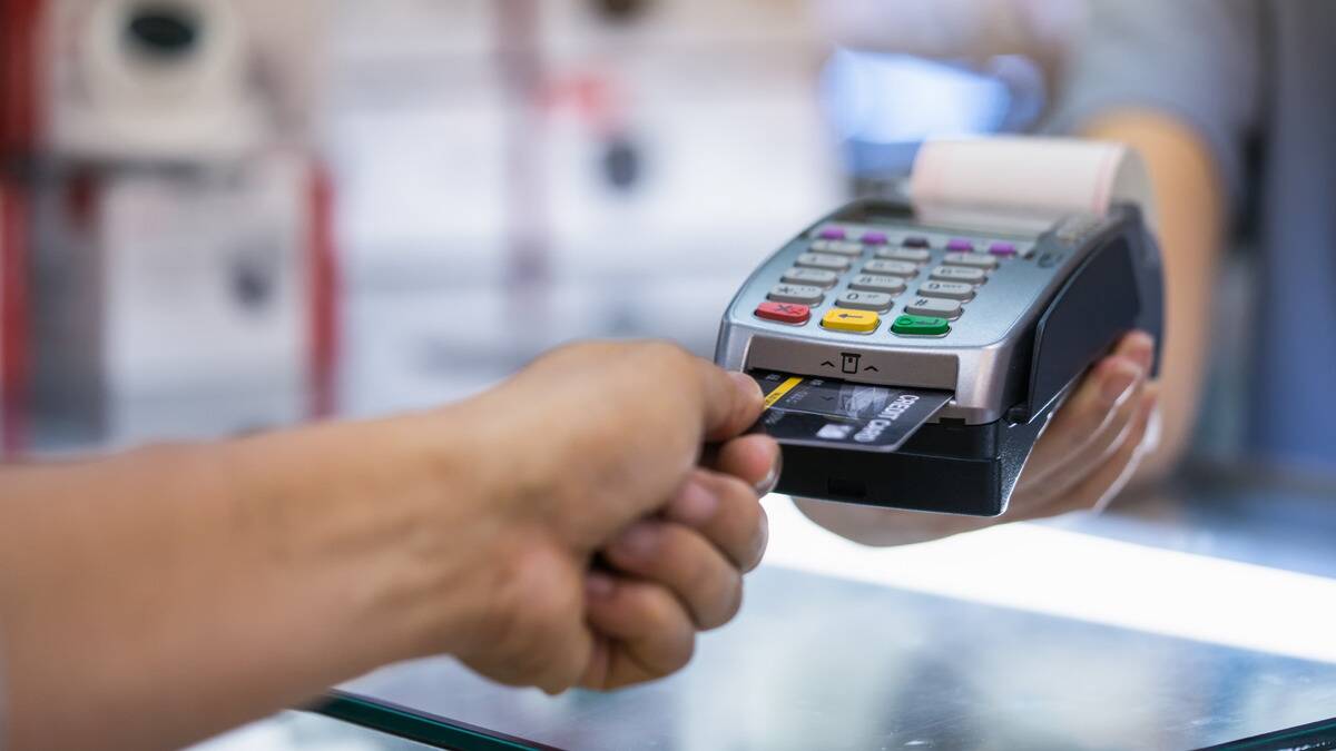 Someone pulling their credit card out of a payment machine.