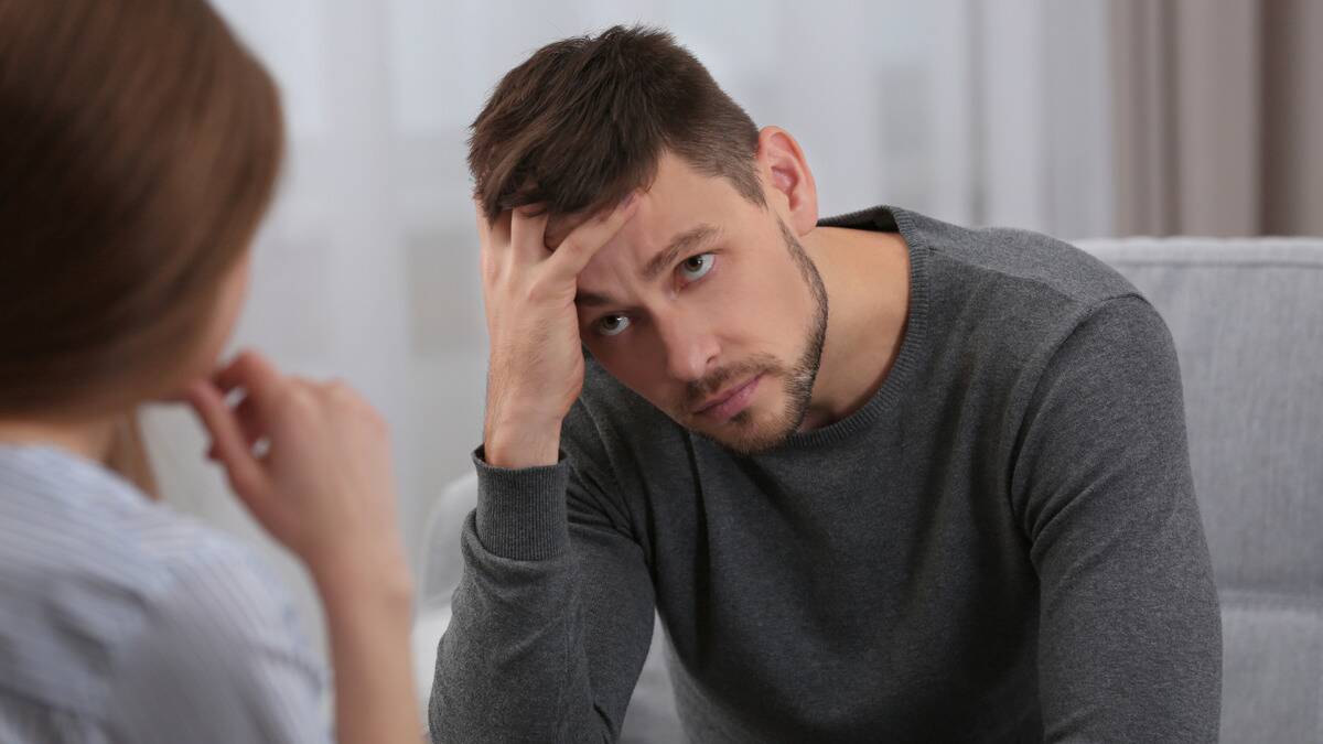 A man with his forehead in his hand, looking exasperated at the woman in front of him.